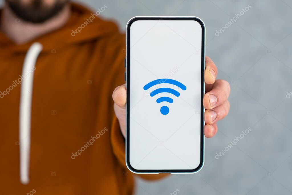 Phone display with wi-fi icon on gray background. Man holds a smartphone in his hand close-up