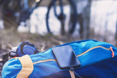 Taşınabilir şarj aleti akıllı telefondan şarj oluyor. Elektrik Bankası, ahşap ve bisikletin arka planında kabloyla.