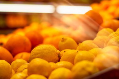 Mağaza vitrininde bir yığın taze meyve portakalı ve limon.