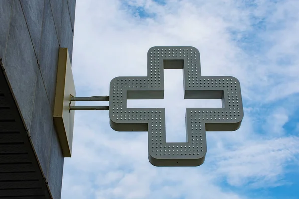 Pharmacy cross in the background against the sky with clouds