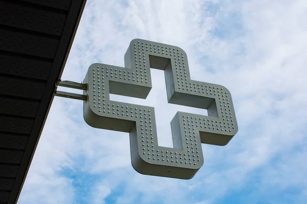 Pharmacy cross in the background against the sky with clouds