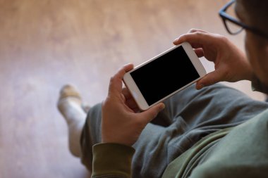 Adam elinde siyah bir ekranla akıllı telefonun maketini tutuyor.