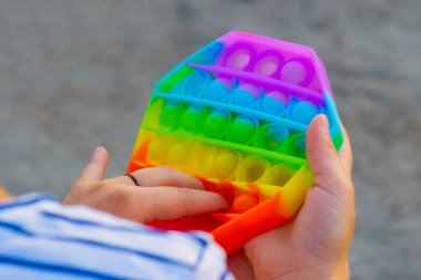 Çocuk renkli bir gökkuşağı poppit oyunuyla oynuyor. Silikon hareketli yakın plan