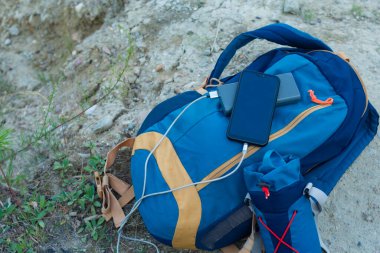 Akıllı telefon taşınabilir şarj aleti ile şarj edilir. Elektrik Bankası açık havada telefon faturasını turizm için bir sırt çantasıyla kesiyor.