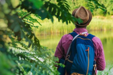 Bir turist seyahat için sırt çantasıyla gölün kıyısında duruyor. Turizm konsepti