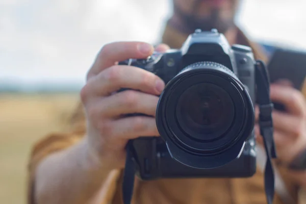 Traveler photographer with a camera in his hand against the background of a field and haystacks