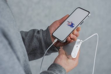 Telefonunda hızlı teslimat var. Elinde güç bankası ve simgesi olan bir akıllı telefonu elinde tutan bir adam.