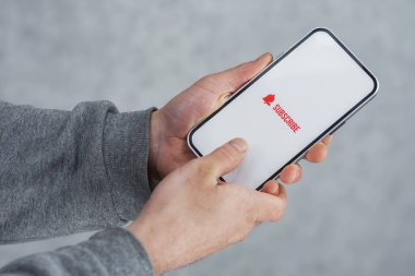 Akıllı telefon ekranındaki internet kanalına abone ol. Adam akıllı telefonu simgeyle yakın plan çekiyor