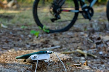 Elektrik bankası, bisiklet arka planında bir akıllı telefonu şarj ediyor.