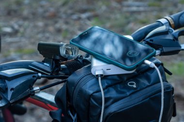 Elektrik bankası, bisiklet arka planında bir akıllı telefonu şarj ediyor.