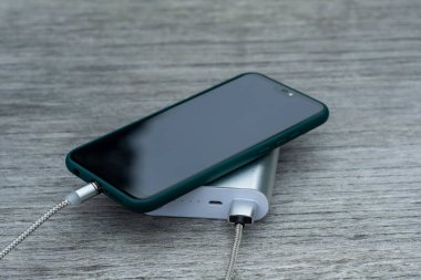 Güç Bankası parktaki ahşap bir bankta akıllı telefondan para alıyor.