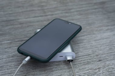 Güç Bankası parktaki ahşap bir bankta akıllı telefondan para alıyor.