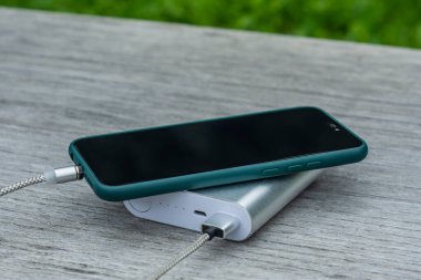 Güç Bankası parktaki ahşap bir bankta akıllı telefondan para alıyor.