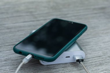 Güç Bankası parktaki ahşap bir bankta akıllı telefondan para alıyor.