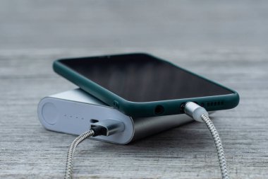 Güç Bankası parktaki ahşap bir bankta akıllı telefondan para alıyor.