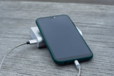 Güç Bankası parktaki ahşap bir bankta akıllı telefondan para alıyor.