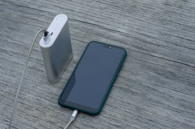 Güç Bankası parktaki ahşap bir bankta akıllı telefondan para alıyor.