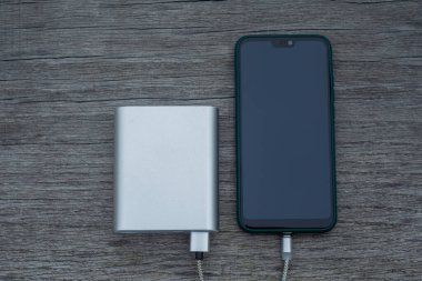 Güç Bankası parktaki ahşap bir bankta akıllı telefondan para alıyor.