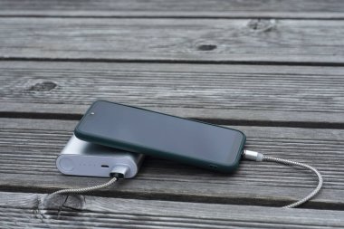 Güç Bankası parktaki ahşap bir bankta akıllı telefondan para alıyor.