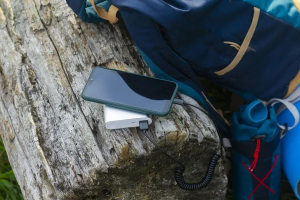 Smartphone is charged using a portable charger. Power Bank charges the phone outdoors with a backpack for tourism in nature