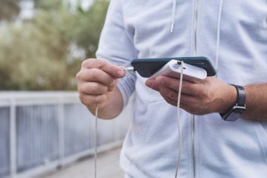 Adam elinde bir güç bankasıyla akıllı telefonu şarj ediyor. Cihazları şarj etmek için taşınabilir şarj cihazı