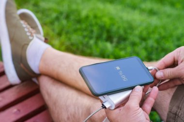 Adam elinde bir güç bankasıyla akıllı telefonu şarj ediyor. Cihazları şarj etmek için taşınabilir şarj cihazı