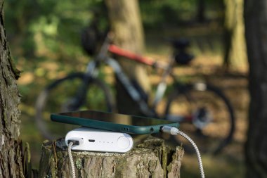 Elektrik bankası, bisiklet arka planında bir akıllı telefonu şarj ediyor.