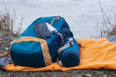 Akıllı telefon taşınabilir şarj aleti ile şarj edilir. Elektrik Bankası açık havada telefon faturasını doğa ve nehir arka planında turizm için bir sırt çantasıyla ödüyor.