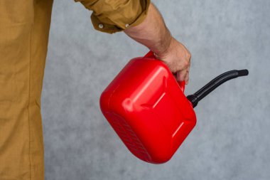 Adamın elinde kırmızı plastik bir gaz tüpü var.