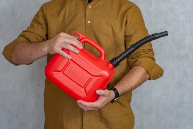 Adamın elinde kırmızı plastik bir gaz tüpü var.