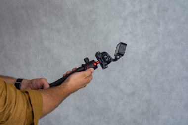 Hafif bir arka planda, esnek bir tripodun üzerindeki sıkıştırılmış aksiyon kamerası