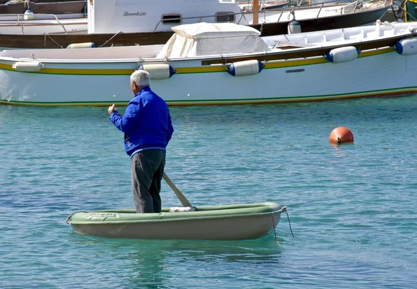 Homem remando um pequeno barco através da baía — Fotografia de Stock