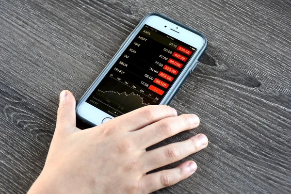 Osoba, která drží iphone při kontrole ceny akcií — Stock fotografie