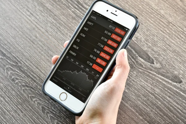 株価を見ながら、iphone を保持 — ストック写真