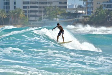 Surfers riding waves on Condado beach clipart