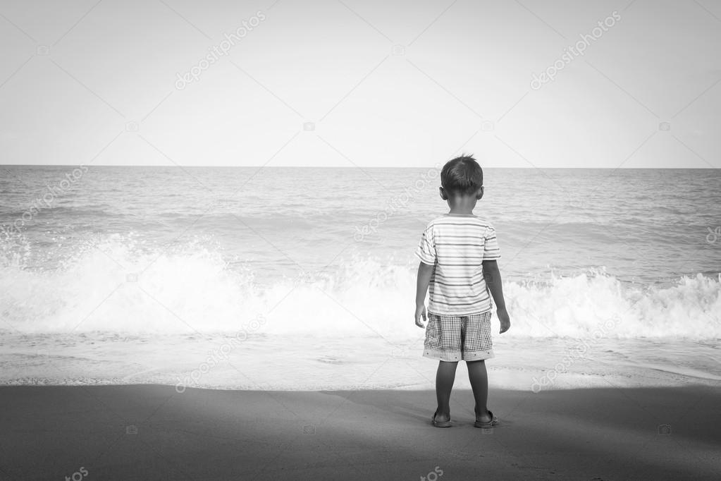 rear of little boy stanging looking the sea,black and white tone