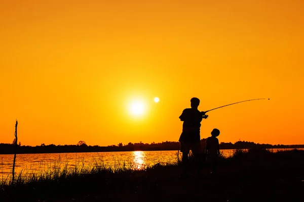 Vader en zoon vissen in de rivier zonsondergang achtergrond — Stockfoto