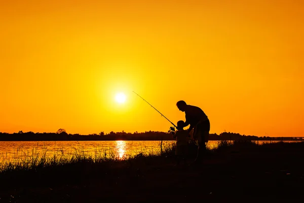 Pai e filho pesca no rio pôr do sol fundo — Fotografia de Stock