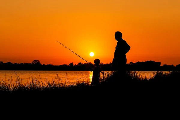 Apa és fia, horgászat a folyó naplemente háttérben — Stock Fotó