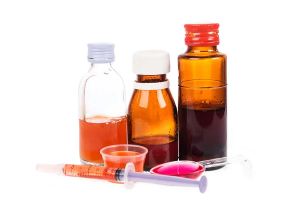 Sirup-Medikamentenflaschen und Medikamente in Löffeln auf weißem Rücken — Stockfoto
