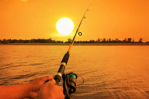 Main homme pêche dans rivière coucher de soleil fond — Photo