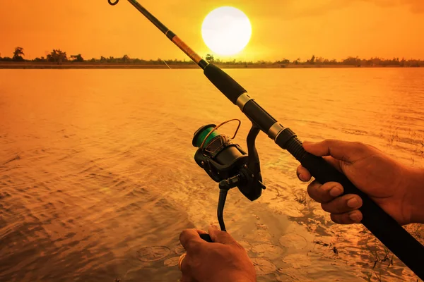 Mão homem pesca no rio pôr do sol fundo — Fotografia de Stock