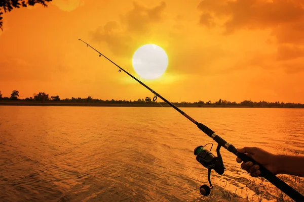 Mão homem pesca no rio pôr do sol fundo — Fotografia de Stock