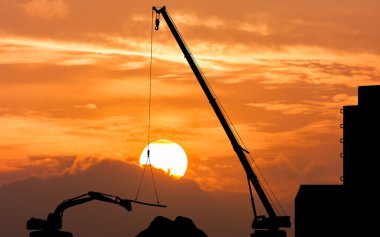 silhouette of excavator and crane working sunset background clipart