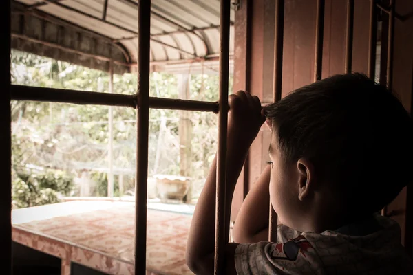 Piccolo ragazzo mano in prigione guardando fuori dalla finestra — Foto Stock