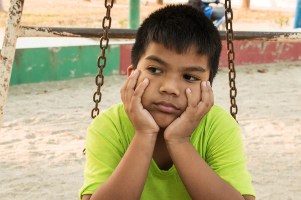 Мальчик грустит один на детской площадке — стоковое фото