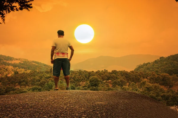 A fiatalember állt a kő-hegy naplemente háttér — Stock Fotó