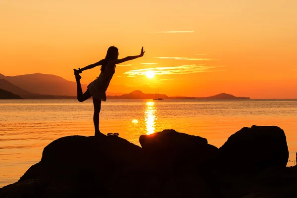 Giovane donna che pratica yoga sullo sfondo tramonto spiaggia — Foto Stock