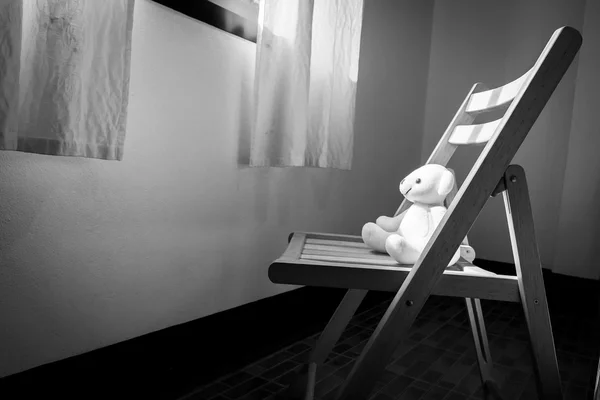 Schattige teddybeer alleen zittend op de stoel in de buurt van venster — Stockfoto