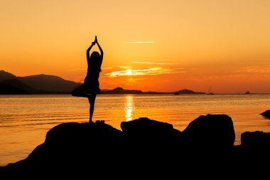 Pratik yoga plaj gün batımı ba üzerinde genç kadın silüeti